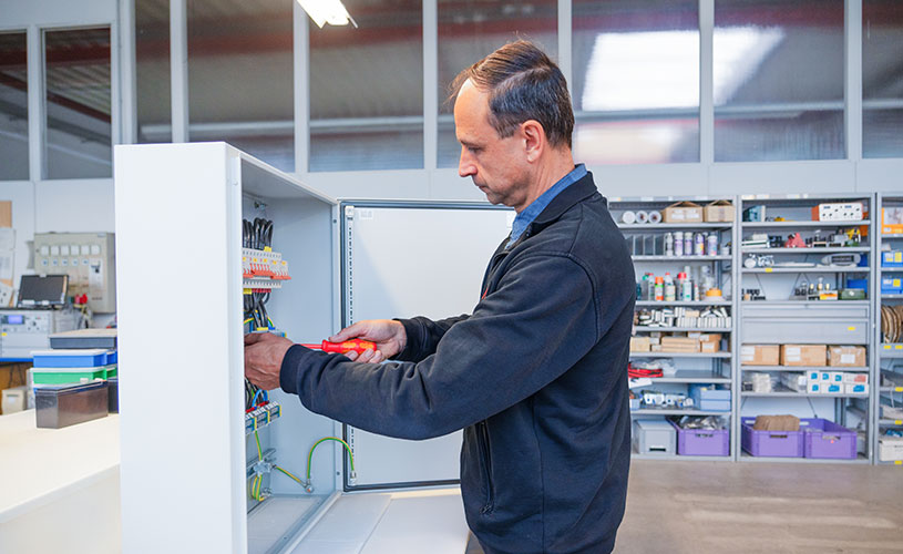 Ein EFFEKTA-Mitarbeiter repariert ein Bauteil einer USV-Anlage und verbindet Kabel mit einem Schraubendreher.