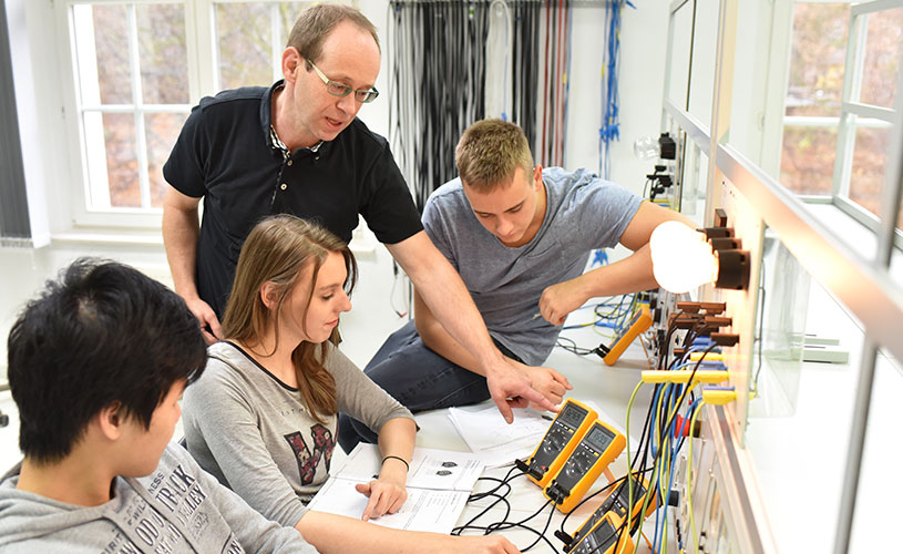 Junge Auszubildende und Ausbilder im Klassenzimmer während einer technischen Berufsausbildung in der Industrie.