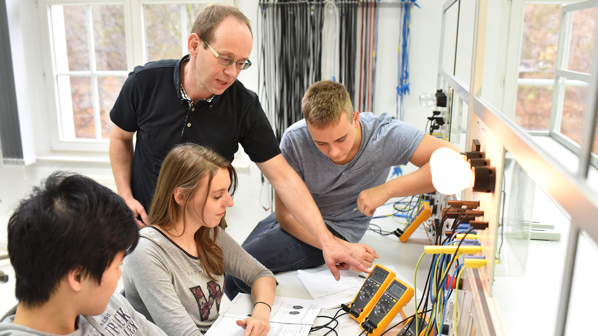 Junge Auszubildende und Ausbilder im Klassenzimmer während einer technischen Berufsausbildung in der Industrie.