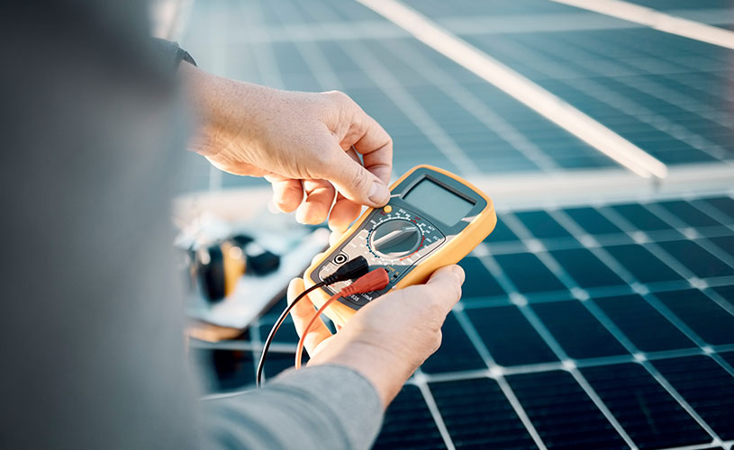 Hände mit Messgeräte welches Werte einer Photovoltaikanlage misst.